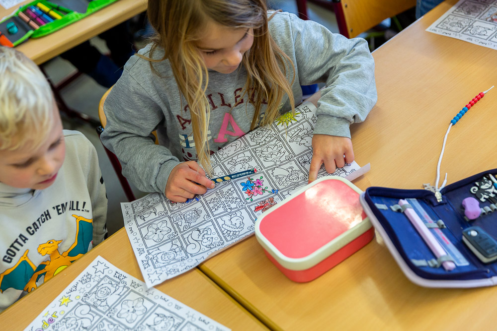 Zwei Kinder sitzen an einem Tisch, ein Kind hat eine Stift in der Hand Zwei Kinder sitzen an einem Tisch, ein Kind hat eine Stift in der Hand