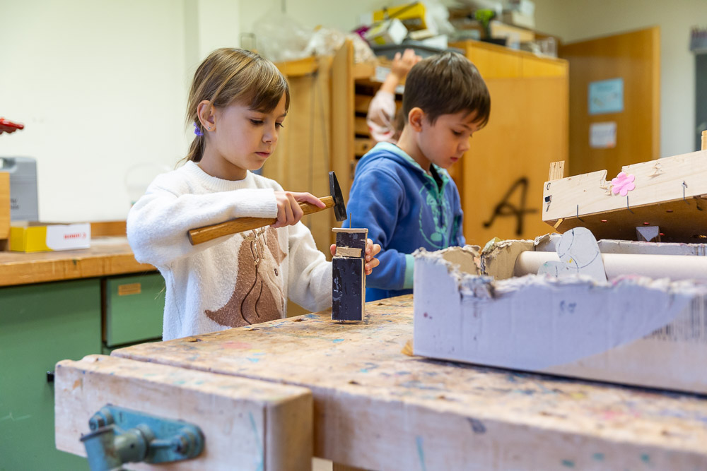 Zwei Kinder im Werkunterricht, ein Kind hat einen Hammer in der Hand Zwei Kinder im Werkunterricht, ein Kind hat einen Hammer in der Hand